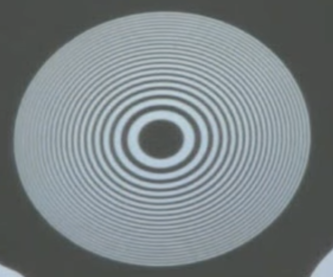 Fresnel zone plate used in the lecture (left), which actually cracked due to the heat of the light source a second later. The Fresnel zone plate creates a focal point as visible on the right (bright spot in the center).